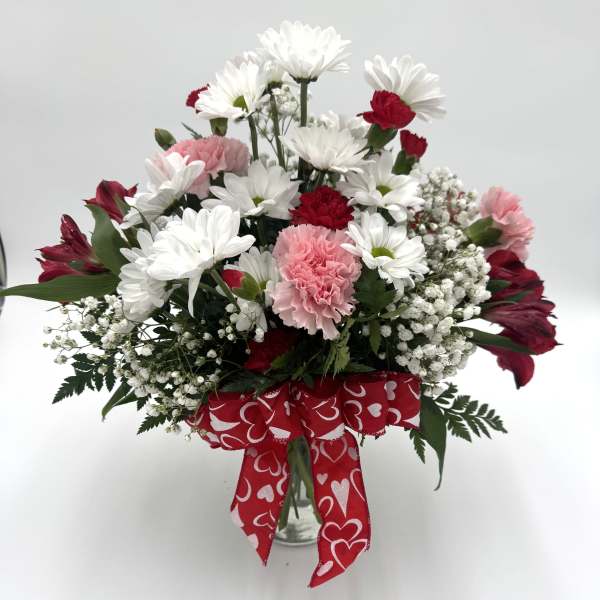 Bouquet of white daisies and pink carnations with a red heart ribbon
