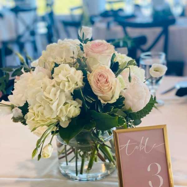 White and blush floral centerpiece in a glass vase on a table
