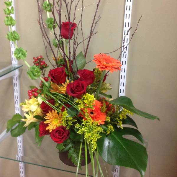 Tall mixed bouquet with red roses and orange gerbera daisies in a vase