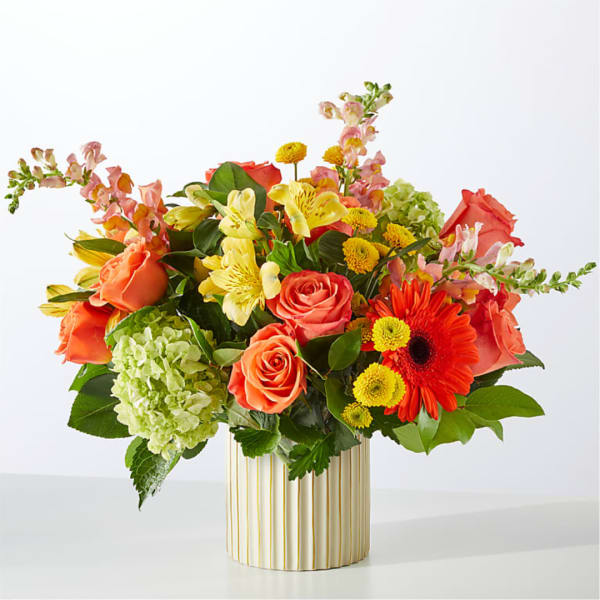 Mixed bouquet of roses, lilies, and gerbera daisies in a striped vase
