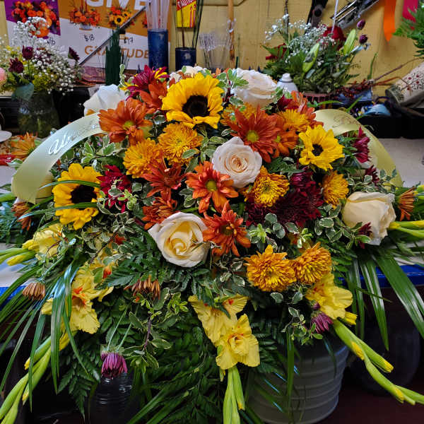 Large mixed floral arrangement with sunflowers, roses, and mums
