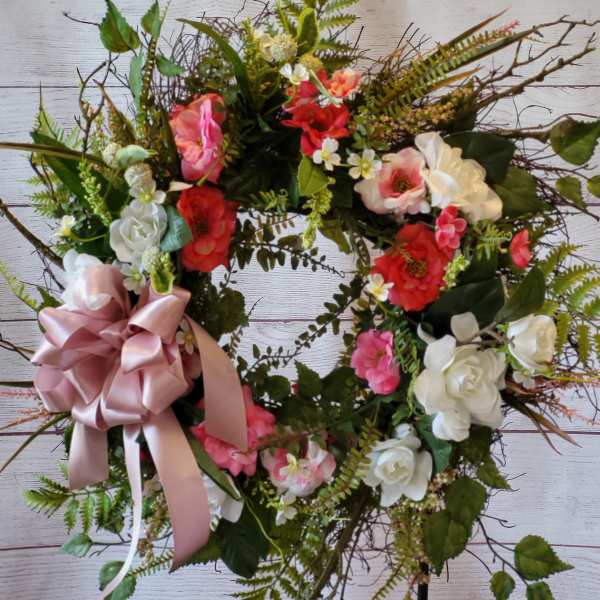 Heart-shaped floral wreath with pink and white flowers and a satin bow