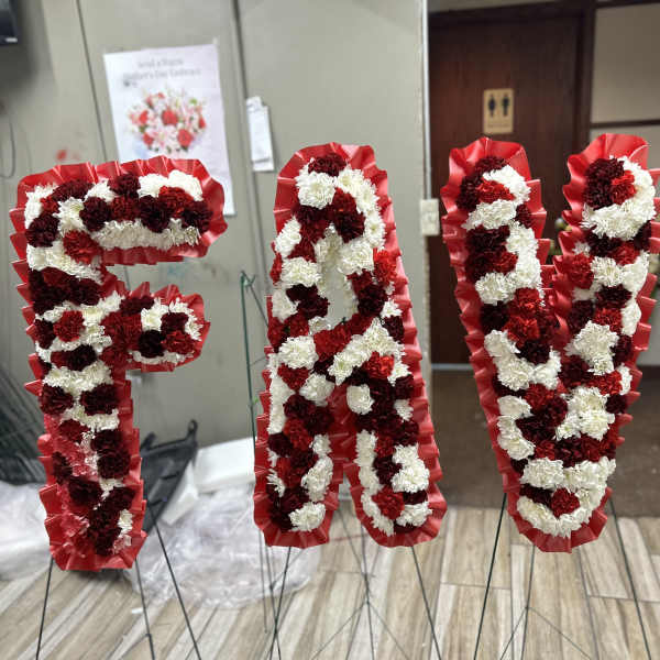 Four red, white, and burgundy floral letter stands on wire easels.