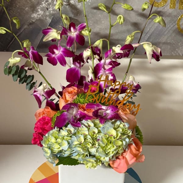 Colorful bouquet with orchids, hydrangeas, and roses in a white box