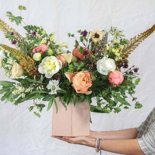 Mixed bouquet in a pink box with peach, white, and burgundy blooms