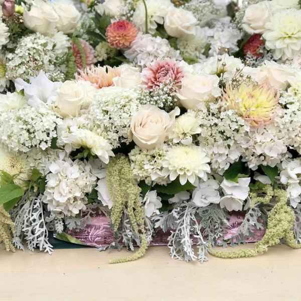 Large white floral arrangement with pale pink and yellow blooms