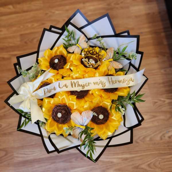 Yellow flower bouquet with butterflies and a ribbon on a wooden floor