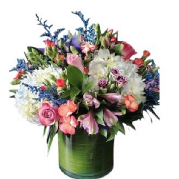 Mixed bouquet of pink, white, and purple flowers in a green glass vase