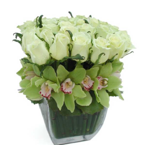 White roses and green orchids in a glass vase