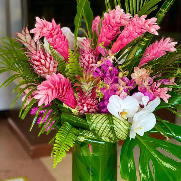 Pink tropical flowers arranged in a green vase with white orchids