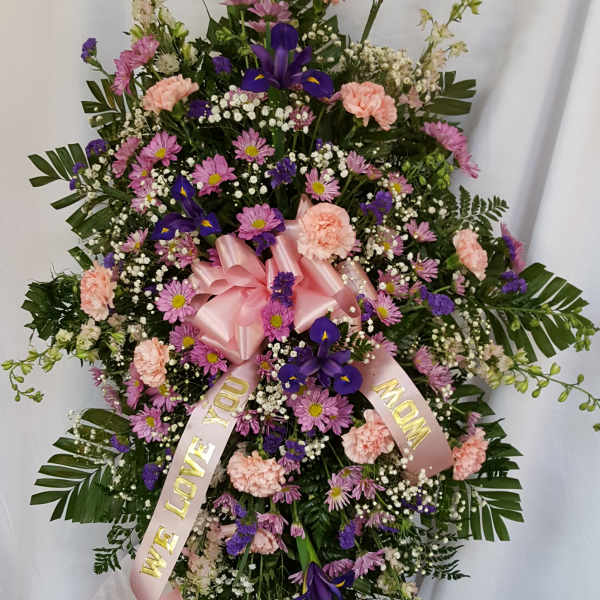 Standing floral spray with pink ribbon and purple flowers