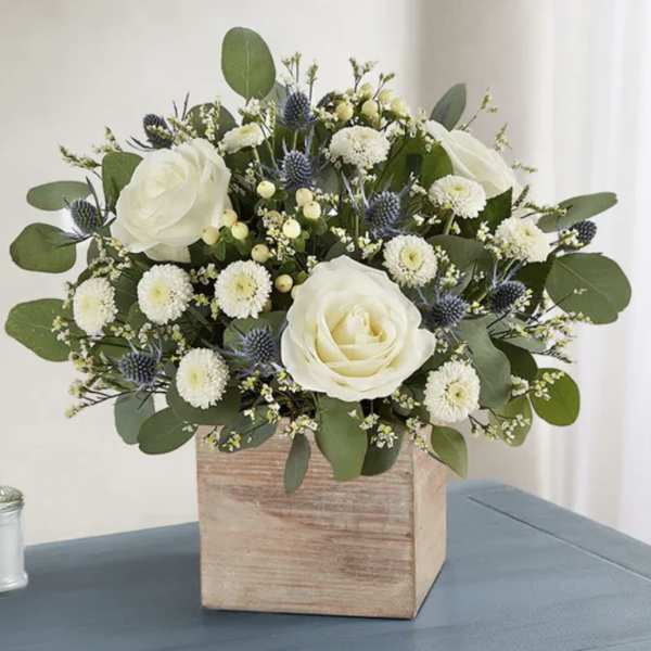 White roses and small white blooms in a wooden box