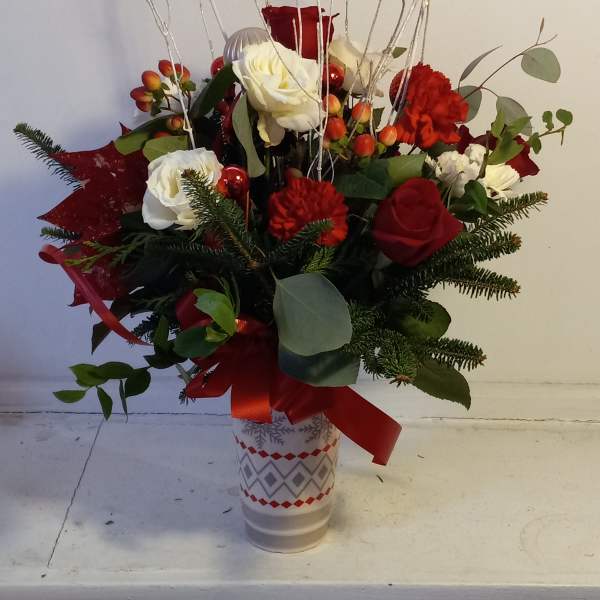 Holiday bouquet of red and white roses in a patterned vase