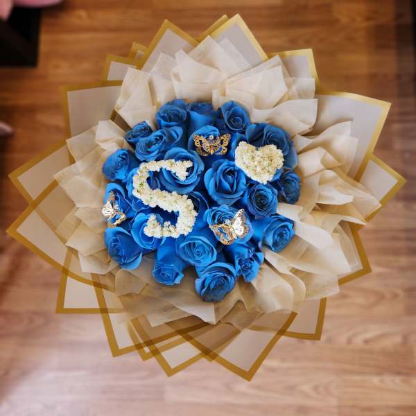 Blue rose bouquet with white letter decorations and butterfly accents