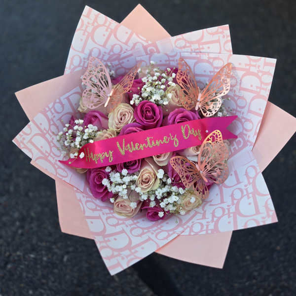 Pink and cream rose bouquet with butterfly decorations and a Valentine ribbon