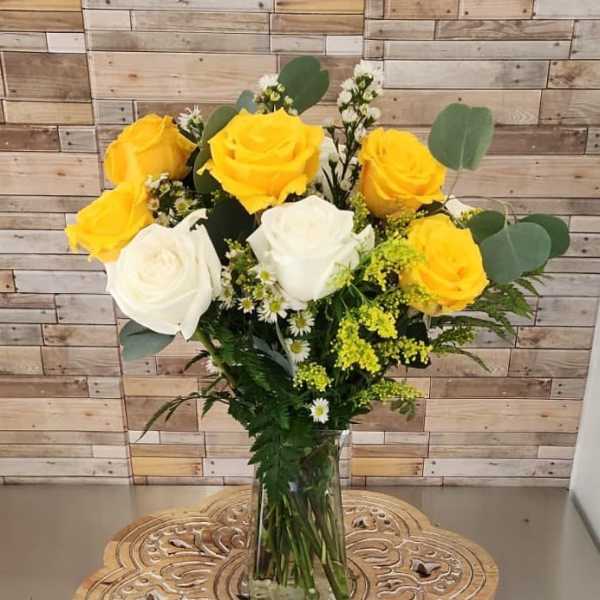 Yellow and white roses in a clear glass vase