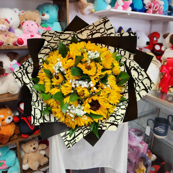 Bouquet of yellow sunflowers with white filler flowers wrapped in patterned paper