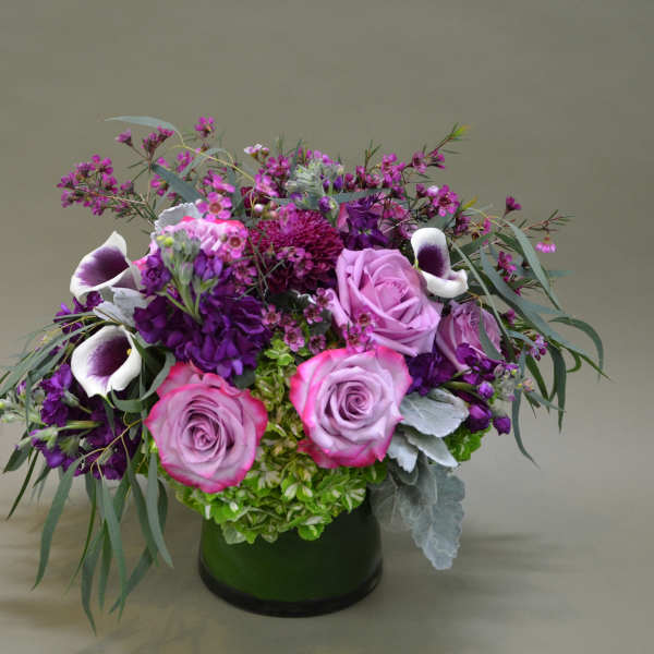 Purple and pink floral arrangement in a dark vase