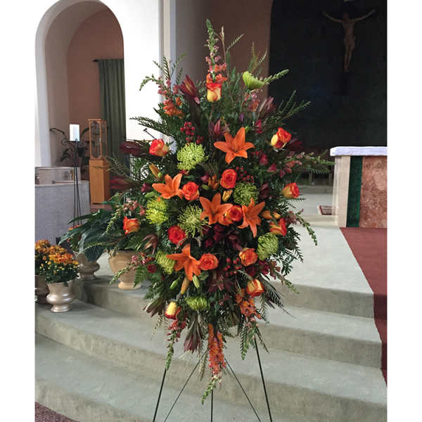 Tall floral spray with orange lilies and roses on a stand