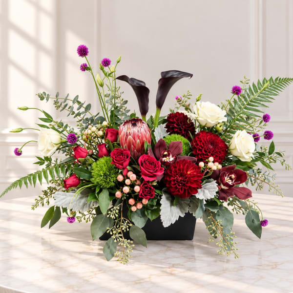 Mixed floral arrangement in a black rectangular vase with red, white, and purple blooms