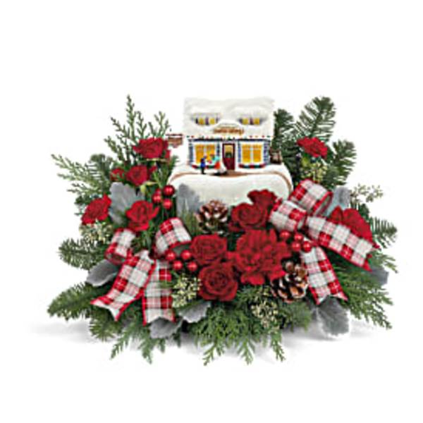 Christmas floral arrangement with red roses and plaid ribbons around a house ornament