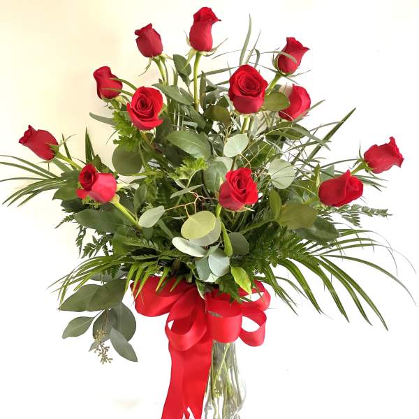 Bouquet of red roses in a clear glass vase with a red ribbon