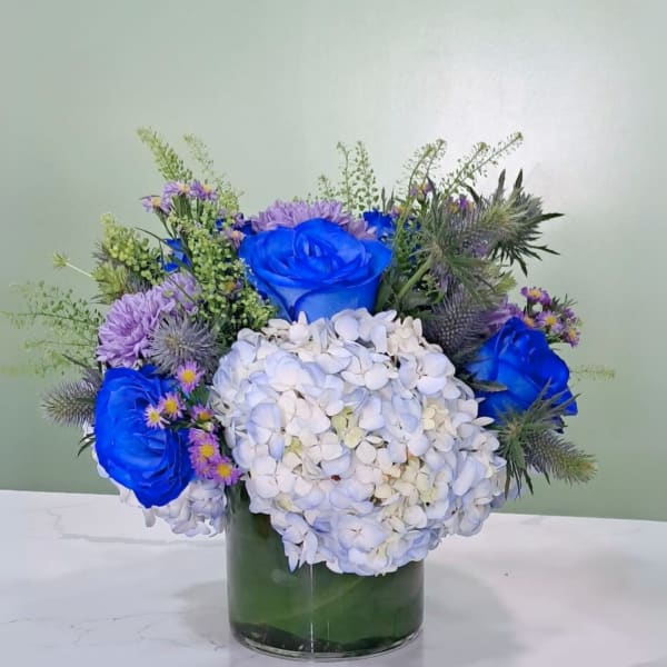 Blue roses and white hydrangeas in a glass vase