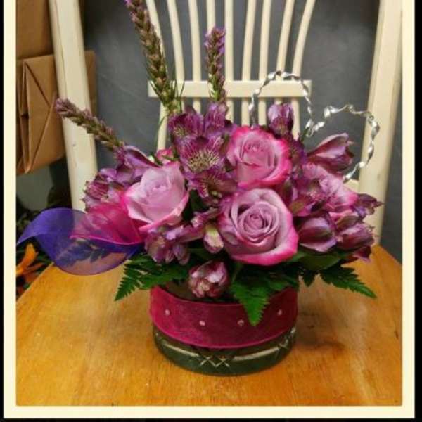 Pink roses and purple flowers arranged in a round glass vase
