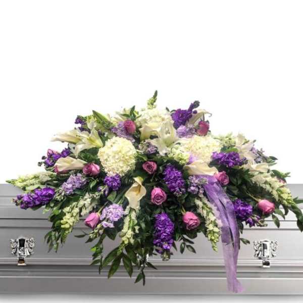 Lavender and white funeral spray on a silver casket