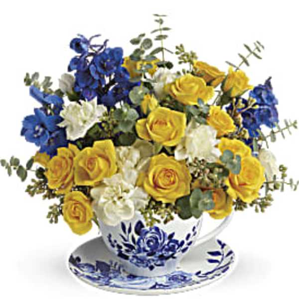 Yellow and blue roses arranged in a blue-and-white teacup and saucer