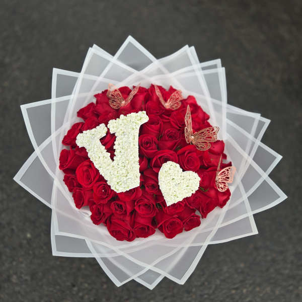 Round bouquet of red roses with white floral letters and butterfly accents