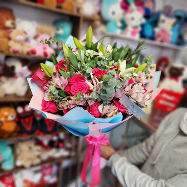 Bouquet of pink roses, lilies, and alstroemeria wrapped in pastel paper