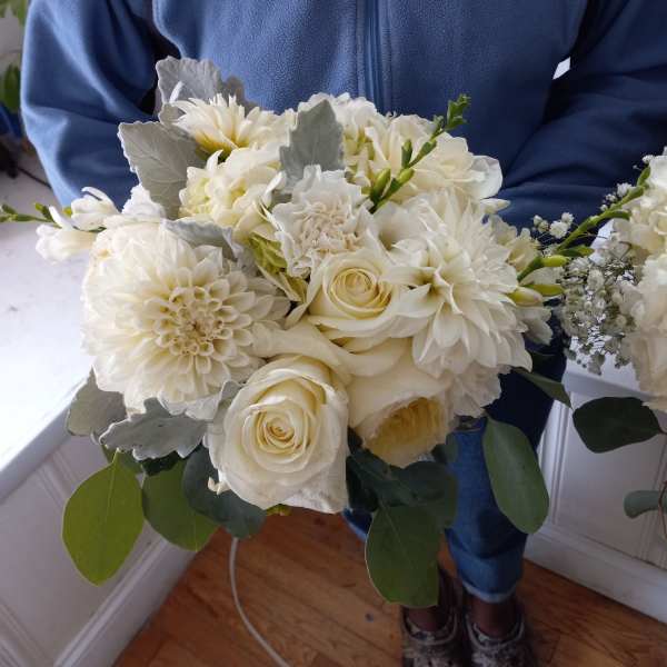 Person holding a white bouquet with roses and dahlias