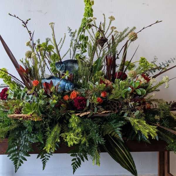 Large floral arrangement with fish decorations and mixed greenery