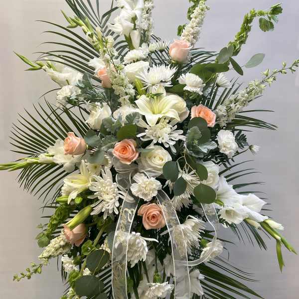 Tall white floral standing spray with peach roses and ribbon
