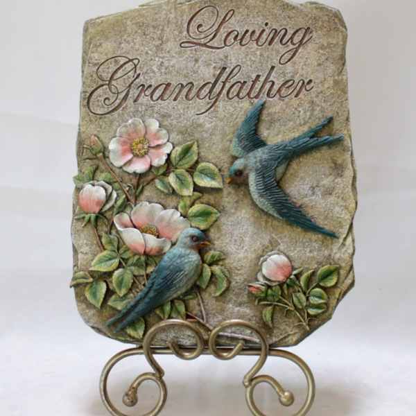 Decorative stone plaque reading "Loving Grandfather" with birds and flowers