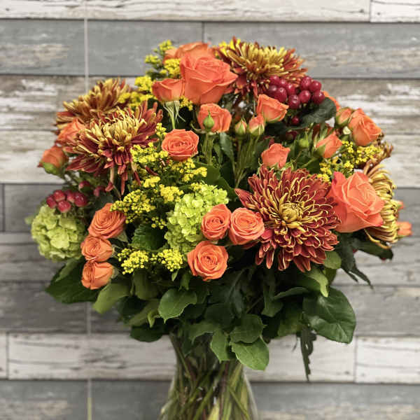 Orange roses and chrysanthemums in a clear glass vase