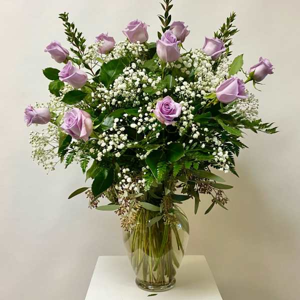 Lavender roses in a clear glass vase with white baby's breath