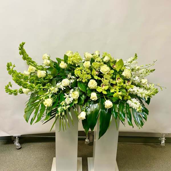 Large white and green floral arrangement on a pedestal stand