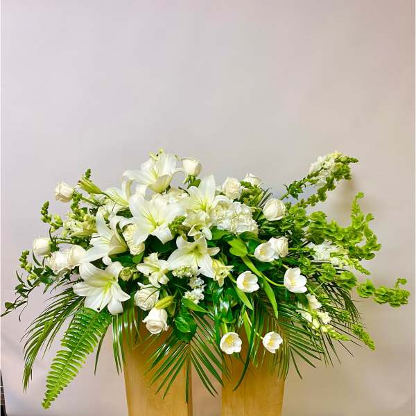 White lilies and roses arranged in a tall gold vase