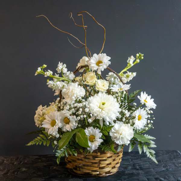 White flowers arranged in a wicker basket with tall curly branches