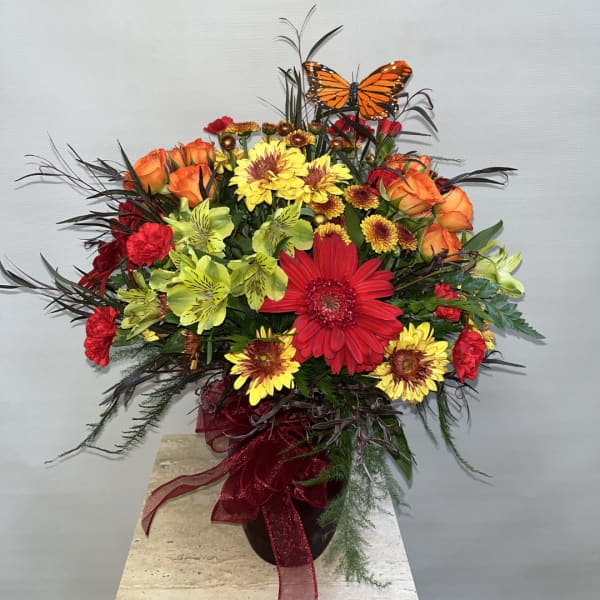 Colorful mixed bouquet in a dark vase with a butterfly pick