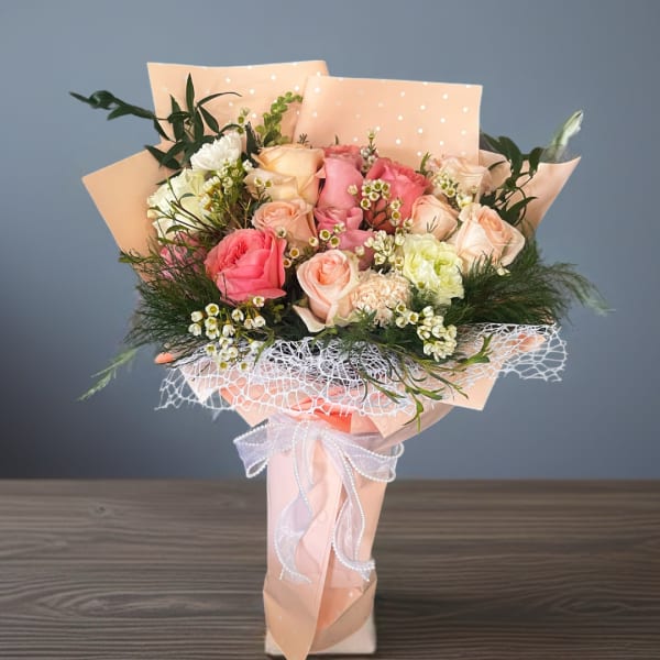 Bouquet of pink and peach roses wrapped in pastel paper
