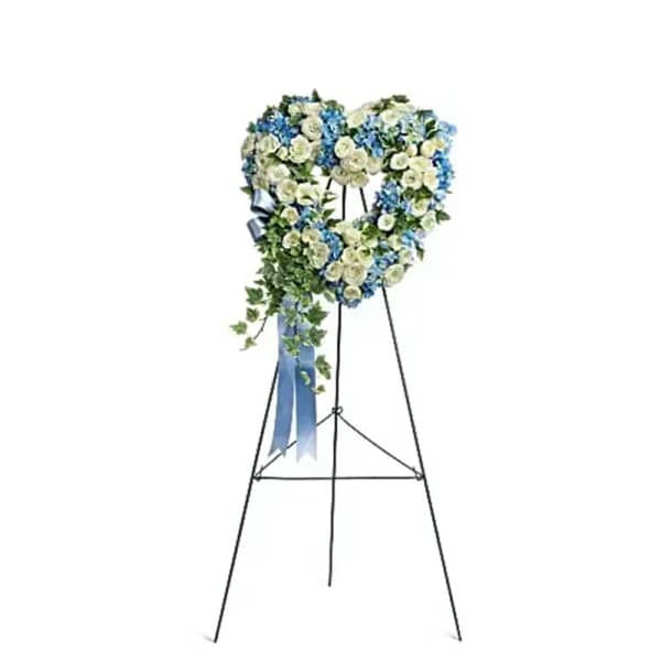 Heart-shaped floral wreath on a black easel with blue ribbon