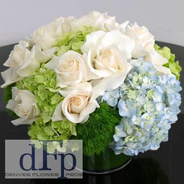 White roses and pale hydrangeas arranged in a low round bouquet