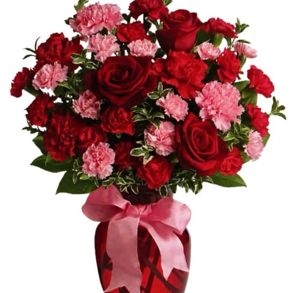 Red roses and pink carnations in a vase with a pink ribbon