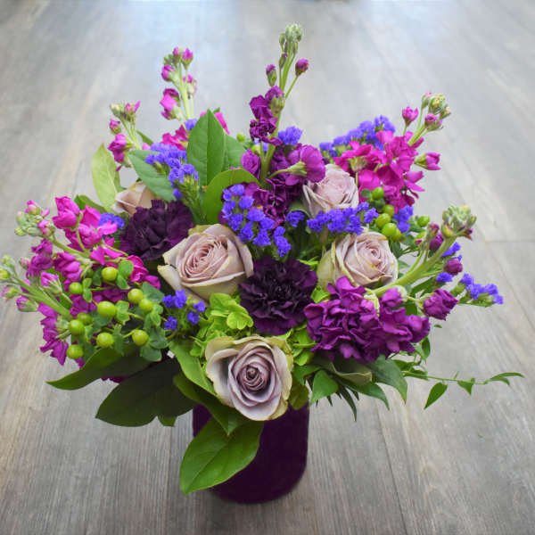 Purple and pink mixed bouquet in a dark vase