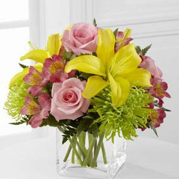 Pink roses and yellow lilies in a clear glass vase