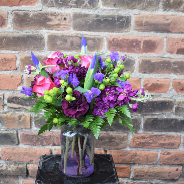 Pink and purple flower arrangement in a glass jar vase