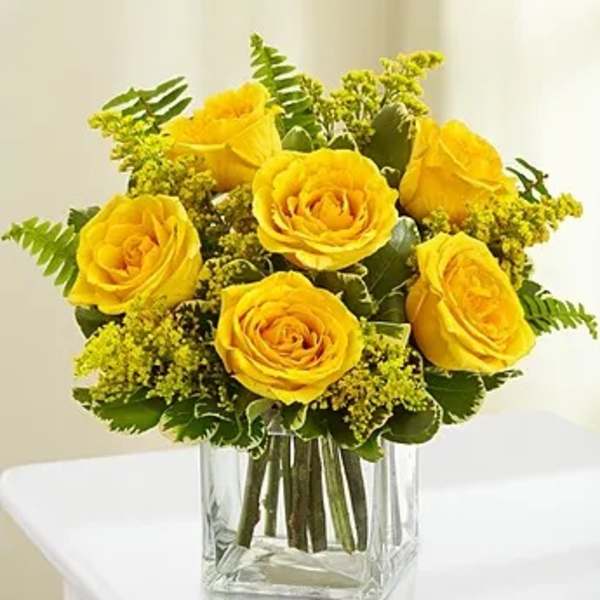 Yellow roses arranged in a clear square glass vase